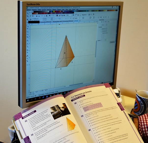 Een wiskundeboek ligt open voor een computerscherm. Zowel in het boek als in het scherm zijn een afbeelding van een vierhoekige piramide te zien.