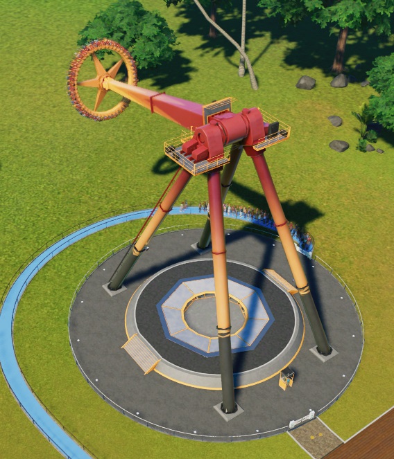 Vogelperspectief van een Sun Dial tijdens de rit. Deze Attractie bestaat uit een lange arm, 'opgehangen' aan een vierpotig frame. Aan de arm hangt een ronde gondel, met naar buiten gekeerde zitplaatsen. De arm zwaait heen en weer; op de foto is hij net naar linksboven uitgezwaaid. Bij de uitgang liggen twee gele braaksel-'vlekken'.