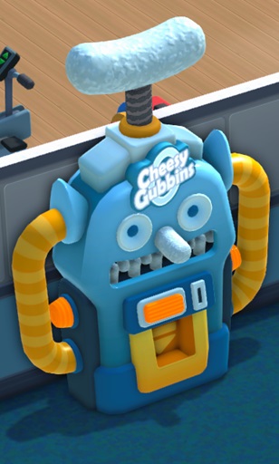 Vogelperspectief van een Cheesy Gubbins Zero-automaat: een machine in de vorm van een robot, met bovenaan een 'gezicht' met een mond vol 'tanden'. Daaronder zit aan iedere zijkant een rond, oranje licht, en een rechthoekig oranje licht op de voorkant. Rechts naast het licht op de voorkant zit het gat voor de munten; daaronder zit de gele uitneemgoot. Aan iedere zijkant zit een lange, gele tube. Bovenop de automaat staat een uitvergrote, lichtblauwe 'Gubbin'.
