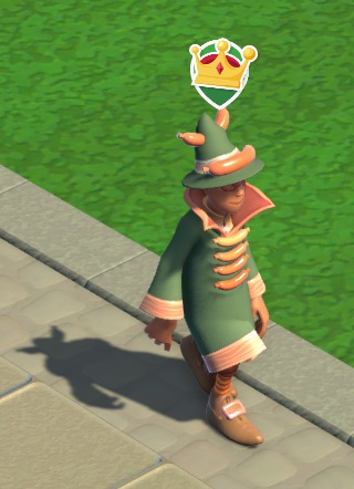 Vogelperspectief van de Meat Wizard-mascotte, die naar rechts wandelt. Ze draagt een groen tovenaarskleed met aan de voorkant, onder elkaar, vier horizontale worstjes. Op haar hoed ligt vooraan een worst; een andere worst steekt dwars door de bovenkant van de hoed heen. Boven haar hoofd zweeft het 'VIP'-icoontje (een kroontje op groene achtergrond).