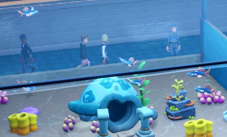 Een Aquarium met zes Flying Fishes en een Egg Cup. Achter het Aquarium lopen Bezoekers voorbij.