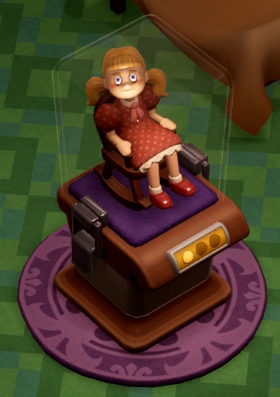 In een afgesloten glazen bak zit een Meisjespop in een kleine schommelstoel. De pop draagt een rood jurkje met roze stipjes, en heeft blond haar en twee paardenstaartjes. Het poppenhoofd is (altijd) naar de speler gericht.