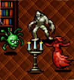 Een kandelaar met drie brandende kaarsen staat in een bibliotheek - linksachter is een gevuld boekenrek te zien. Rond de kandelaar verschijnen van links naar rechts een groen, zwevend hoofd met slangen als hoofdhaar, een wit monster en een rode, vrouwelijke Vampier.