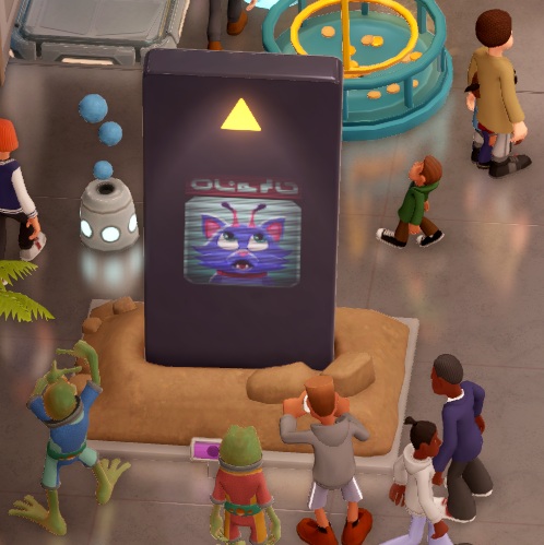 Een enorme Tablet toont een afbeelding van een Kattenkop-met-antennes. Boven de kat staat onleesbare 'buitenaardse' tekst. Bezoekers lopen rond de 'Lone Henge'; één van hen neemt een foto.