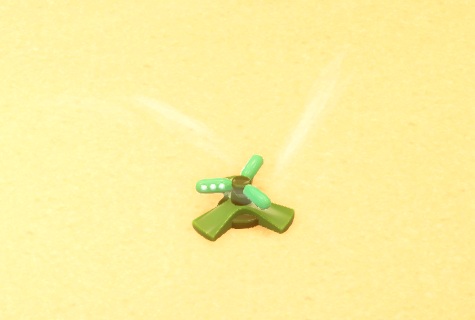 Een groene, drie-armige Sprinkler sproeit zijn water in een Woestijn-Habitat.